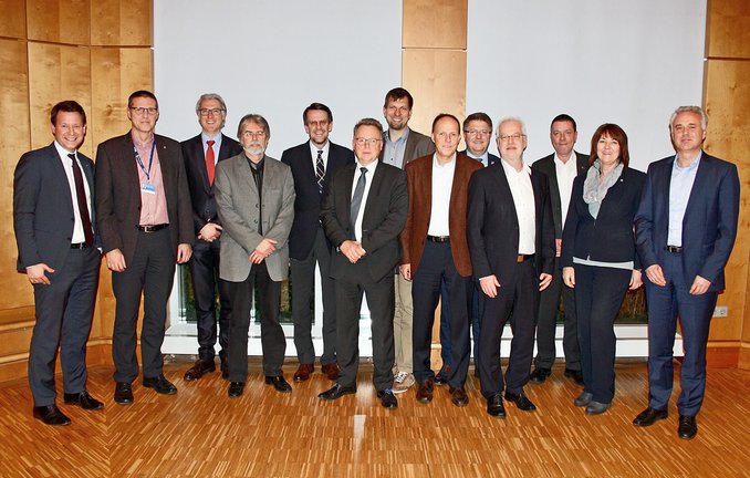 Gruppenfoto von etwa 14 Personen in einem holzvertäfelten Saal